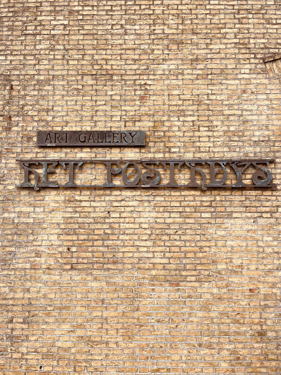 Het Posthuys Art Gallery in De Koog: bronzen letters op een oude Texelse bakstenen muur.